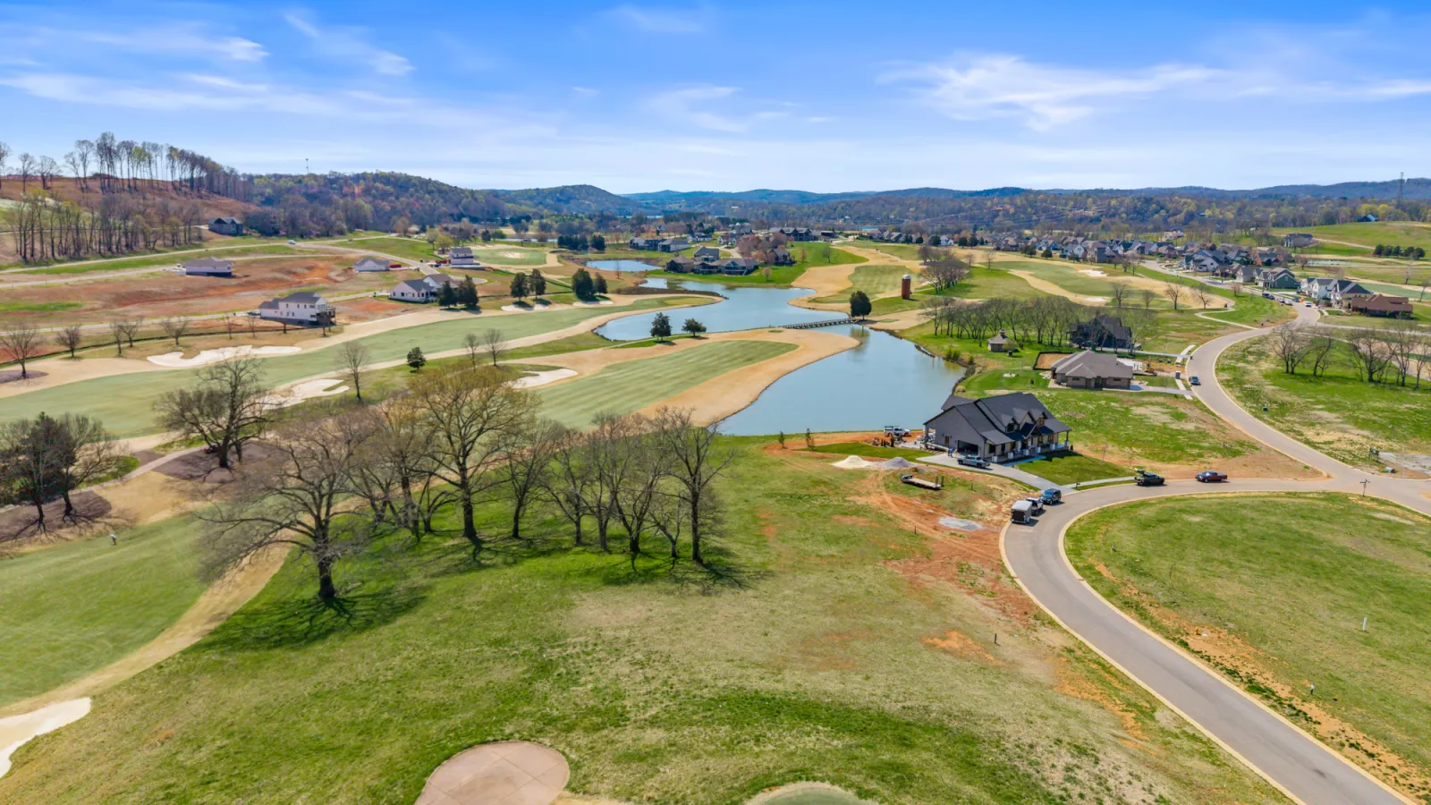 Aerial view across a golf course community with ponds and fairways, rolling hills in the distance